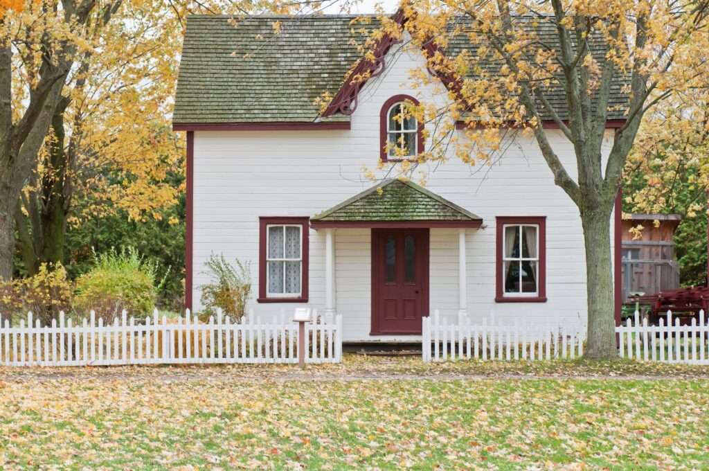 white and red wooden house with fence